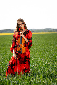 绿色草地上身着红裙、提琴的年轻女子 — 图片