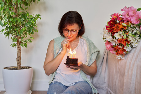 带蜡烛的小生日蛋糕的中年妇女