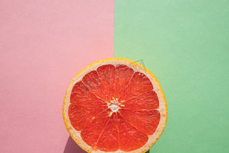 葡萄柚切成宏观、热带创意最小食品水果概念，粉红色绿色背景。成熟葡萄柚片。水果即食。柑橘新鲜水果。排毒、维生素、保健营养
