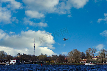 直升飞机在云彩和蓝天的背景下起飞