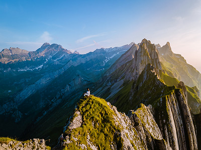 策摄影照片_女人在山上徒步旅行，瑞士舍夫勒 Altenalptuerme 山脊瑞士阿尔卑斯山高山阿彭策尔内罗登，瑞士雄伟的舍夫勒峰的陡峭山脊