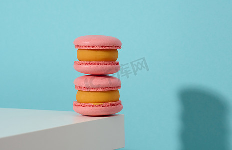 蓝色背景中烤的粉色圆形马卡龙，美味的甜点