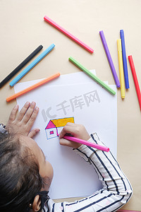 在桌子上的纸上画画的小女孩的俯视图
