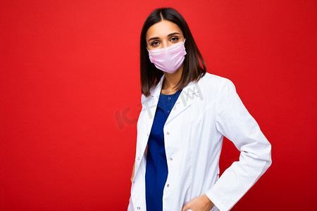 脸上戴着病毒防护面具的褐发女性抵御冠状病毒和背景中突显的白色医用大衣