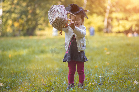 小女巫在秋天的公园里玩一篮树叶。
