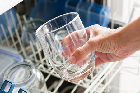 啤酒扔水里摄影照片_女人从洗碗机里拿出杯子