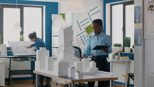 建筑师使用数字平板电脑设计办公室建筑模型和草图的布局