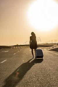 背着行李走在沙漠乡村公路上的女人