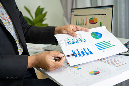 亚洲会计师在现代办公、财务和商业概念中使用图表和计算器工作和分析财务报告项目会计。