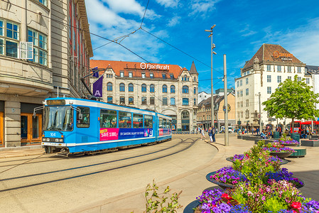 奥斯陆 — 2019年6月，挪威：奥斯陆市中心一条街道上有蓝色电车、古老的历史建筑和美丽的花坛