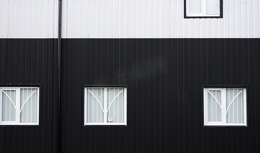 黑白波纹铁皮用作带窗户的仓库或工厂的立面。