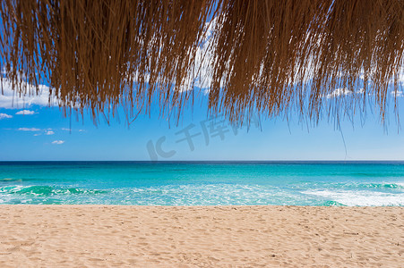 沙滩与美丽的绿松石海水、蓝天和草伞，用于海滩度假背景概念