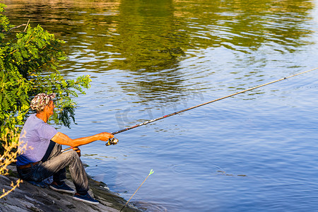 钓鱼竿钓鱼船摄影照片_2020 年，男子在罗马尼亚奥尔索瓦的河边放松和钓鱼