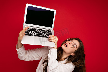 美丽微笑快乐的年轻女子的特写肖像拿着笔记本电脑看着上网本玩得开心穿着休闲智能衣服隔离在墙壁背景