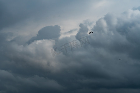 人工播种摄影照片_小飞机在多云的天空中祈雨。