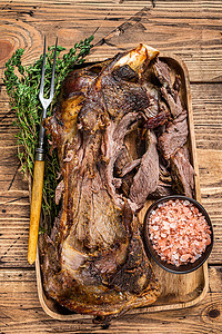 烤羊肉用肉叉在木托盘中切肩肉。