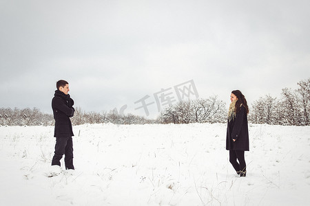 冬天总结摄影照片_一个穿着暖和的衣服和围巾的男孩和女孩在雪天散步