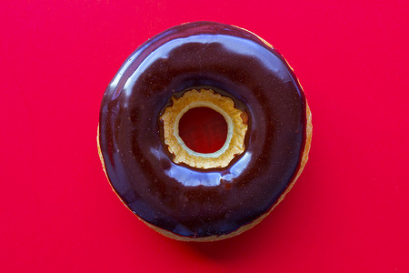 结冰的球摄影照片_红色背景上的巧克力酱甜甜圈