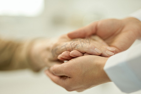 爱心公益墙摄影照片_有爱心的医生握住和检查一名老年患者的手