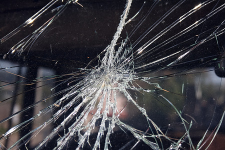 点摄影照片_裂纹和玻璃碎片从被物体击中的窗户的撞击点辐射出来