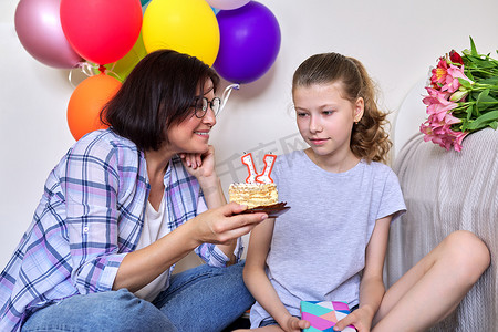带蜡烛、礼物、气球的生日蛋糕的妈妈和女儿