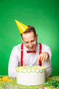 绿色背景中品尝生日蛋糕的男人