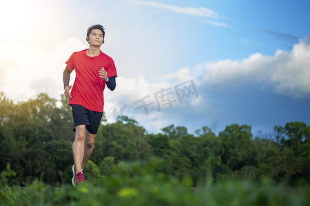 公路奔跑摄影照片_英俊的年轻人在一条乡村道路上为身体健康奔跑