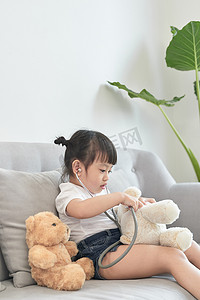 亚洲小女孩玩洋娃娃玩具。亚洲小女孩手里拿着听诊器检查洋娃娃玩具。