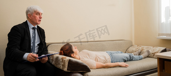 躺沙发摄影照片_在心理治疗师的招待会上，白人女性躺在沙发上。