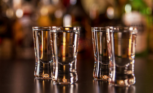 纯黑色摄影照片_酒吧背景酒杯中的传统纯伏特加，酒瓶