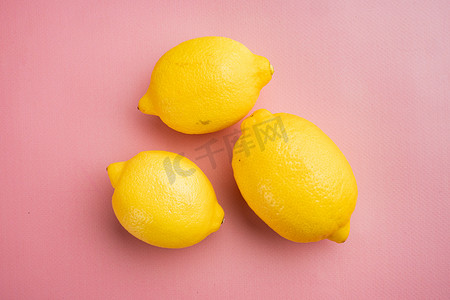 质感背景粉色摄影照片_新鲜成熟的柠檬，粉红色质感的夏季背景