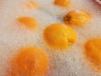 粉红色塑料桶中肥皂水中的橙子
