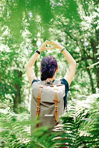丛林探险家摄影照片_徒步旅行者女人用她的手在户外做心形。