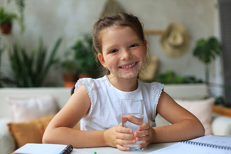 每天摄影照片_快乐的小女孩在玻璃杯里喝水晶矿泉水，小孩建议每天服用干净的水