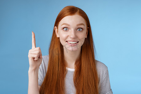 好的看的背景摄影照片_女孩提出了很好的建议想出了一个好主意举起食指尤里卡明白了手势微笑激动想要分享计划团队说话看相机兴奋喜悦，站在蓝色背景