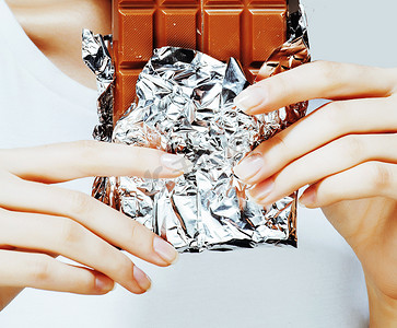 吃巧克力的女人，手上拿着美甲的法式指甲，手里拿着糖果，漂亮的手指，生活方式的概念