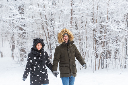 相爱的年轻夫妇在白雪皑皑的森林里散步。