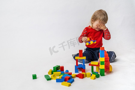 哭泣的小男孩正在玩彩色的木立方体