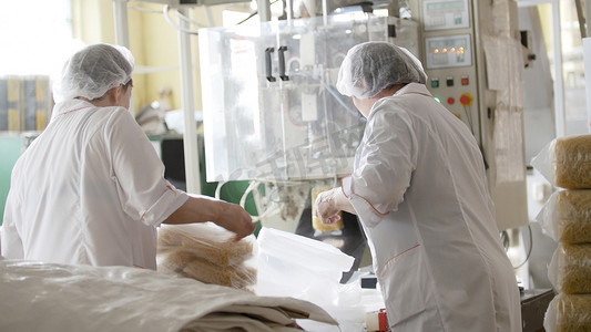 奉献的工人们摄影照片_面食工厂的工人从传送带上包装通心粉