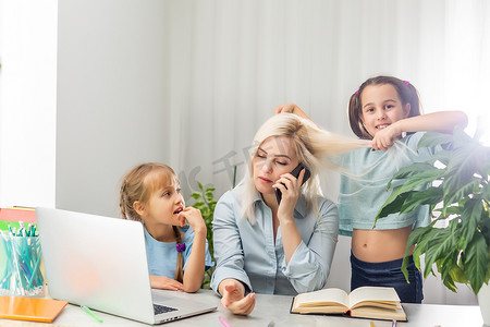 一位带着两个孩子的年轻母亲在家中用电脑工作。
