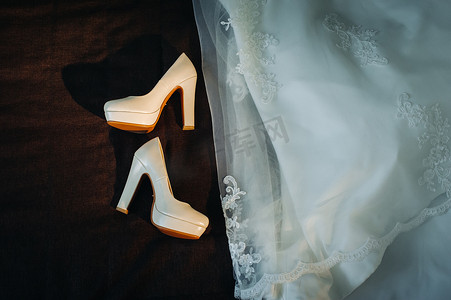 黑色背景中的白色婚鞋和礼服