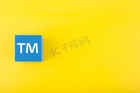 黄色背景蓝色玩具立方体上的 TM 商标标志，带复制空间