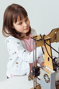 儿童学生在 3D 打印机上制作物品。