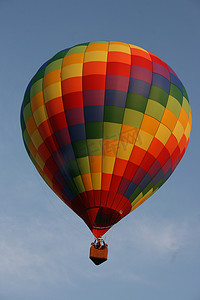 彩虹方块图案的热气球在多云的天空中飞行