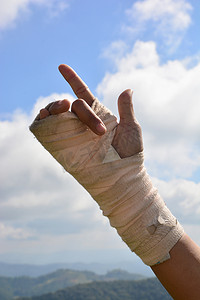 手腕疼痛的人用弹性绷带练习手指与天空背景