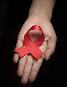 女性手上的红丝带意识：世界艾滋病日缎带象征概念引起人们的关注/帮助运动公​​众对艾滋病毒性病心脏病的支持