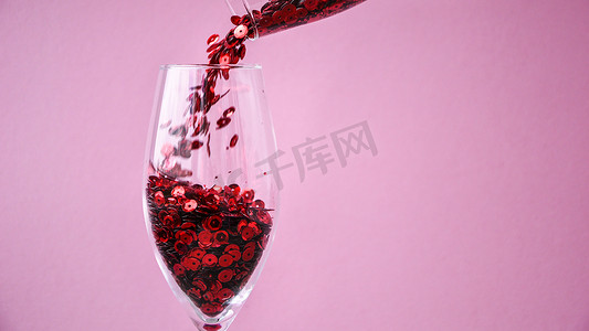 横幅红色五彩纸屑落入粉红色背景的香槟杯中，复制文本空间，创意节日贺卡
