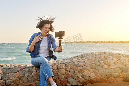 视频秋天摄影照片_中年快乐的女人在网上聊天，在智能手机上录制视频