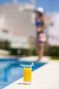 夏季和旅行概念：小型飞机模型和泳池附近的橙汁