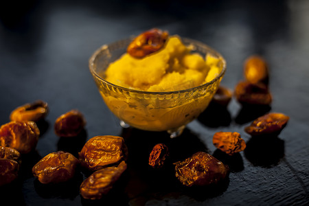 浸泡在酥油中的枣子的特写镜头，以提高黑色木质表面的耐力和健康，以及酥油或澄清黄油。